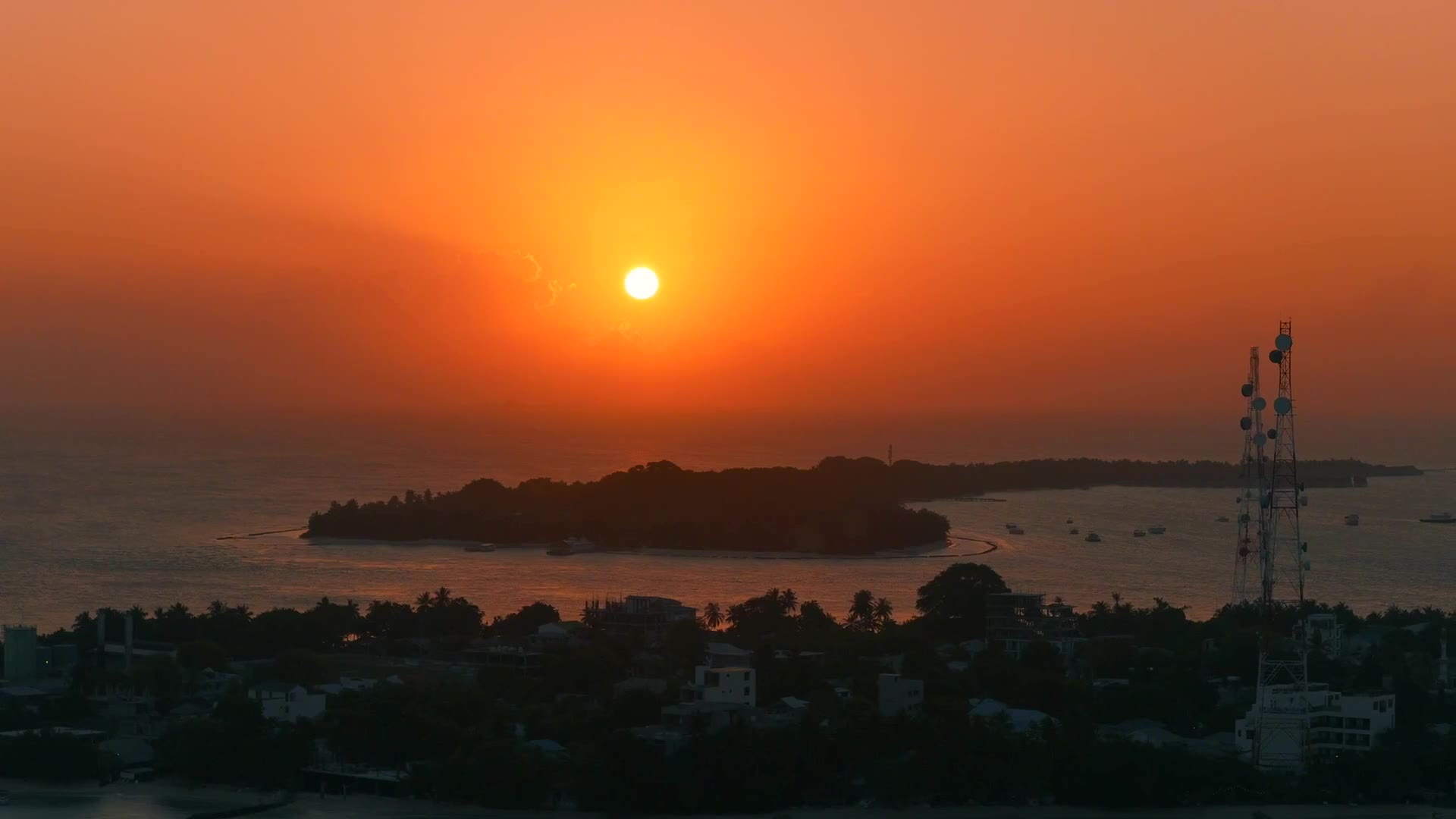 Orange sunset over the Malé city skyline and lagoon
